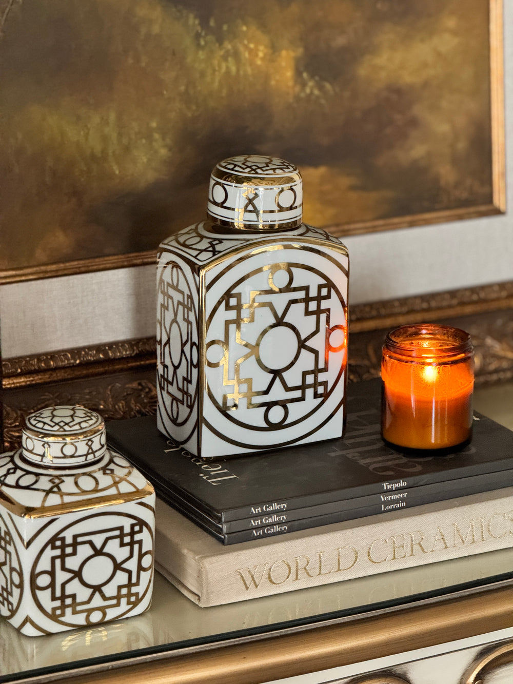 White and gold lattice lidded carafes with an amber candle on art books – Bohemia Lifestyle